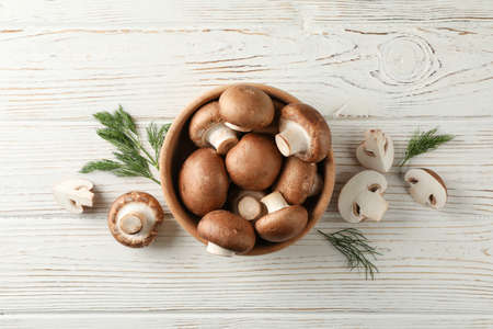 Champignon mushrooms in bowl and dill on wooden background, top viewの写真素材