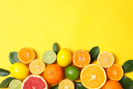 Juicy citrus fruits and leaves on yellow background, space for textの写真素材