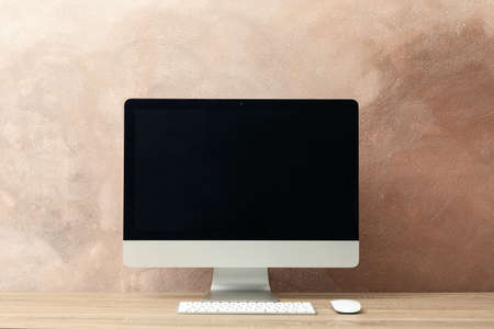 Workplace. Computer, keyboard and mouse on wooden table. Light brown backgroundの写真素材