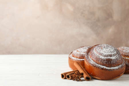 Cinnamon rolls with powdered sugar and cinnamon stacks on white wooden table, copy spaceの写真素材