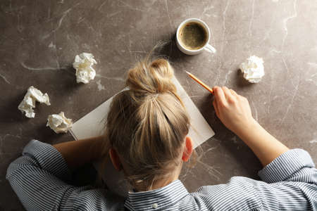 In search of inspiration. Girl, paper balls and cup of coffee on grey background, top view
