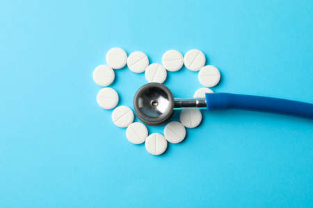 Heart made of pills and stethoscope on blue background, space for textの写真素材