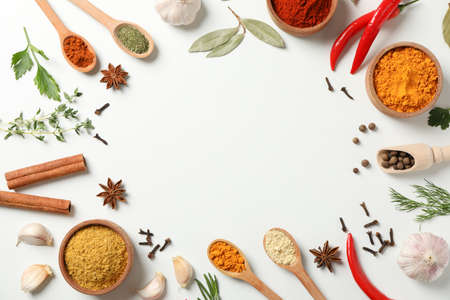 Spoons and bowls with different spices and ingredients on white background, space for text