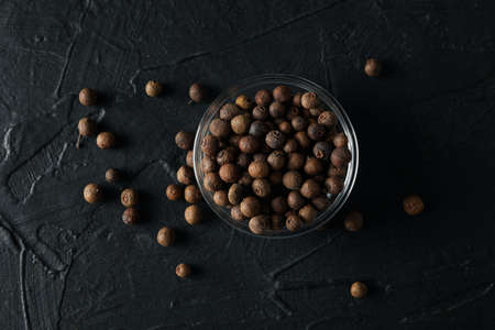 Bowl with peppercorns on black background, top viewの写真素材