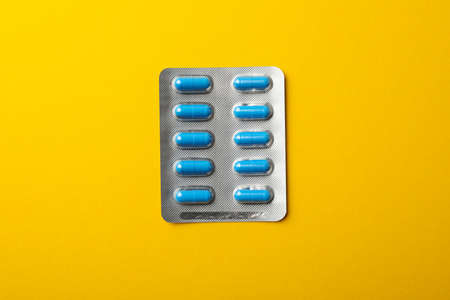 Pills in blister pack on yellow background, space for textの写真素材