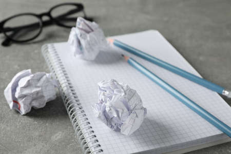 Paper balls, notebook, glasses and pencils on grey table, close upの写真素材