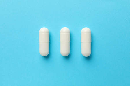 Flat lay with pills on blue background, copy space and top view