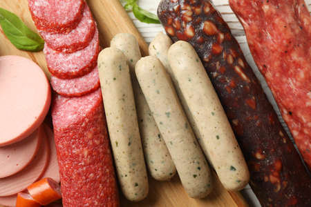 Sausage and basil on wooden background, close up and top view