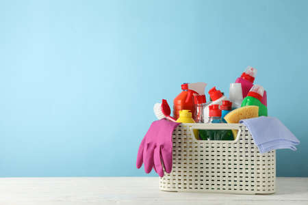 Basket with detergent and cleaning supplies on blue background, space for textの写真素材