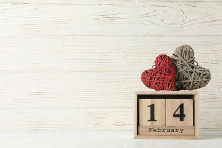 Wooden calendar and decorative hearts on white wood background, space for textの写真素材