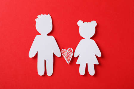 Figures of boy and girl, and decorative heart on red background, close upの写真素材