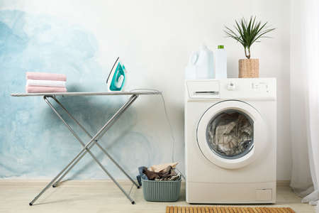 Laundry room with washing machine against light blue wallの写真素材