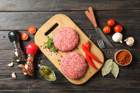 Spices and cutting board with minced meat on wooden background, top viewの写真素材
