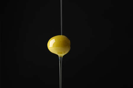 Olive and pouring olive oil on black background, close upの写真素材