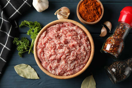 Spices and bowl with minced meat on wooden background, top viewの写真素材