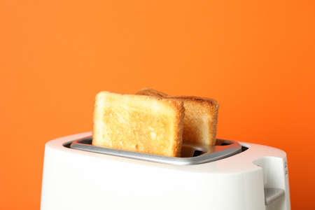 Toaster with bread on grey table against orange background, close upの写真素材