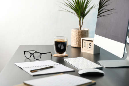 Workplace with computer, glasses and calendar on black wood table, copy spaceの写真素材