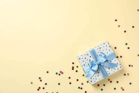 Gift box and star glitter on color background, top view