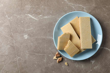 Plate with sweet wafers on grey background, top view
