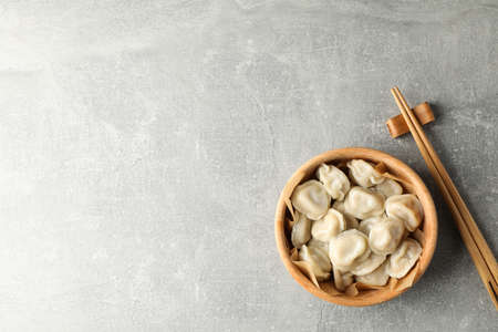 Chopsticks and bowl with dumplings on grey background, space for textの写真素材
