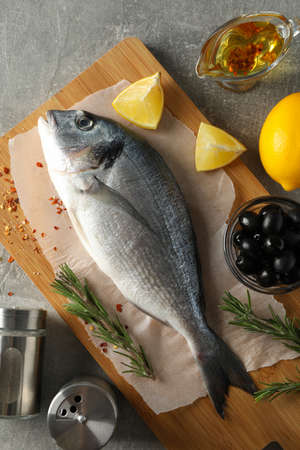 Cutting board with Dorado fish and cooking ingredients on grey background, top viewの写真素材