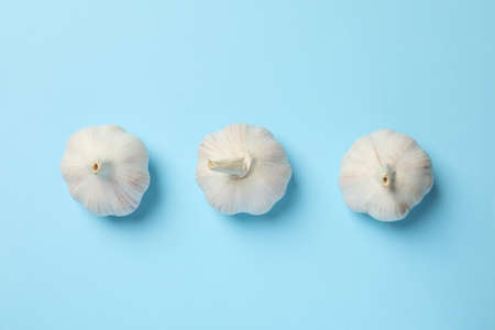Flat lay of fresh garlic bulbs, slices on blue background, top view. Space for text