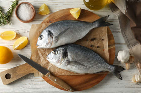 Board with Dorado fishes and cooking ingredients on wooden background, top viewの写真素材