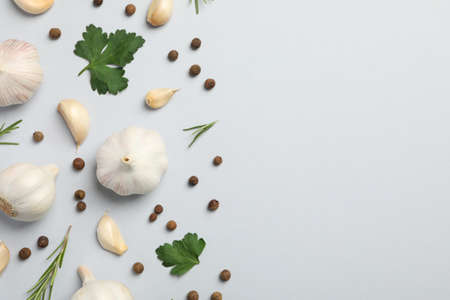 Flat lay of composition, garlic bulbs, slices, spice, parsley, rosemary on grey background, top view. Space for textの写真素材