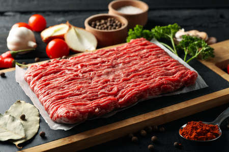 Spices and cutting board with minced meat on wooden background, close upの写真素材