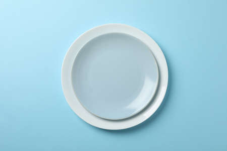 Plates on blue background, top view and space for text