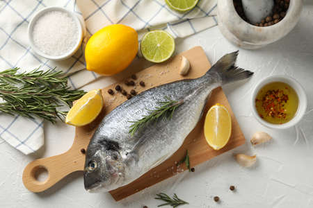 Cutting board with Dorado fish and cooking ingredients on white background, top view