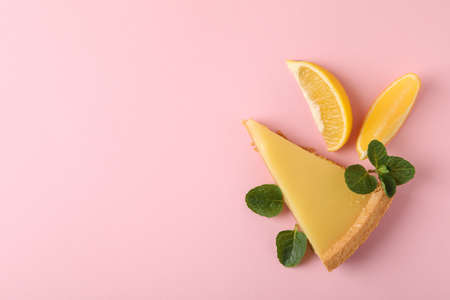 Lemon tart slice and lemon slices on pink background, top view