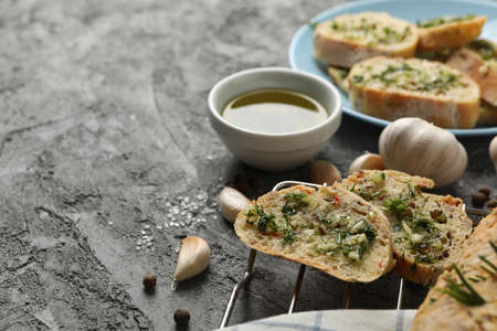 Tasty garlic bread and spices on grey background, close up