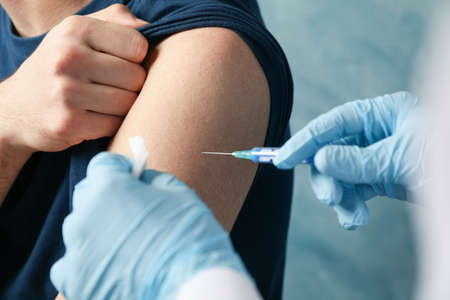 Doctor does an injection patient on blue background. Coronavirus protection. Healthcare and medical...
