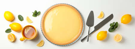 Lemon tart, mint and lemons on white background, top view