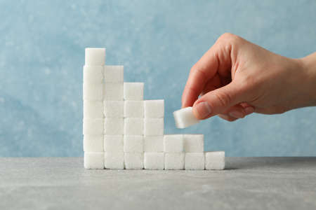 Stairs of sugar and female hand with sugar cube, close upの写真素材