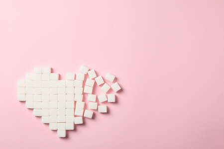 Broken heart made of sugar cubes on pink background, top viewの写真素材
