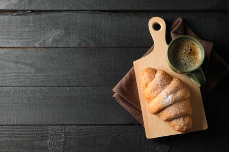 Board with croissant and cup of coffee on wooden background, top viewの写真素材