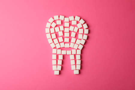 Tooth made of sugar cubes on pink background, top viewの写真素材