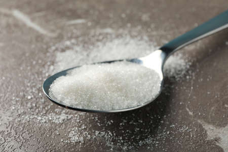 Spoon with sugar on grey background, close upの写真素材