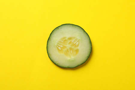 Cucumber slice on yellow background, top viewの写真素材