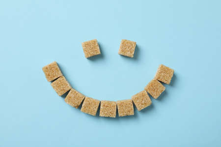 Smiley face made of sugar cubes on blue background, top viewの写真素材