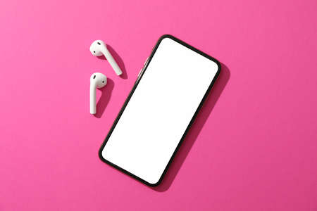 Phone with empty screen and headphones on pink background, top viewの写真素材