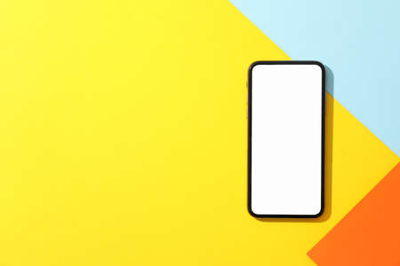Phone with empty screen on multicolored background, top view