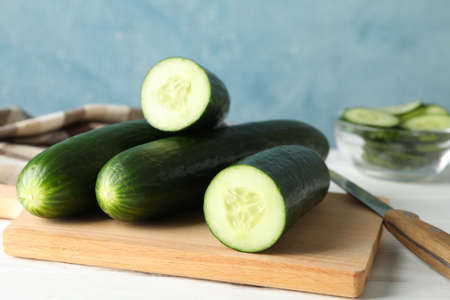 Board and bowl with cucumbers, knife and towel on wooden table, close upの写真素材