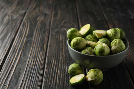 Bowl with brussels sprout on wooden background, space for text