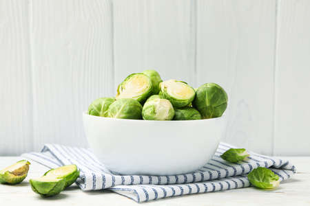 Bowl with brussels sprout on wooden background, space for text