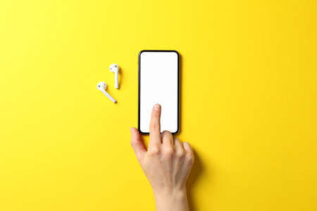Female hand, phone with empty screen and headphones on yellow background, top viewの写真素材