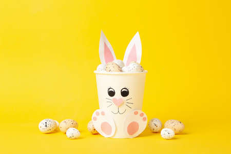 Bunny with Easter eggs on yellow background, space for textの写真素材