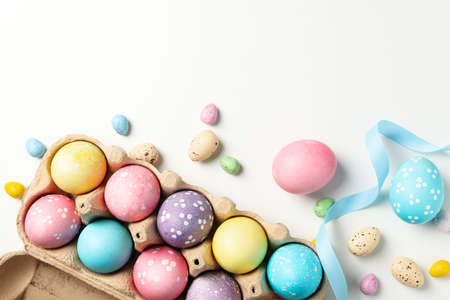 Egg box, Easter eggs and ribbon on white background, top view